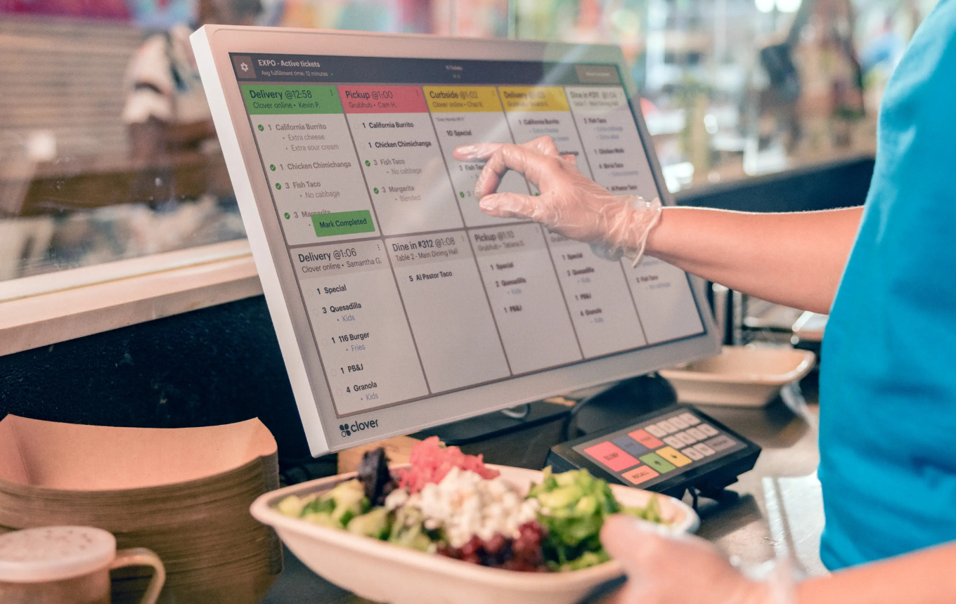 Restaurant staff managing online orders and delivery times on a POS screen