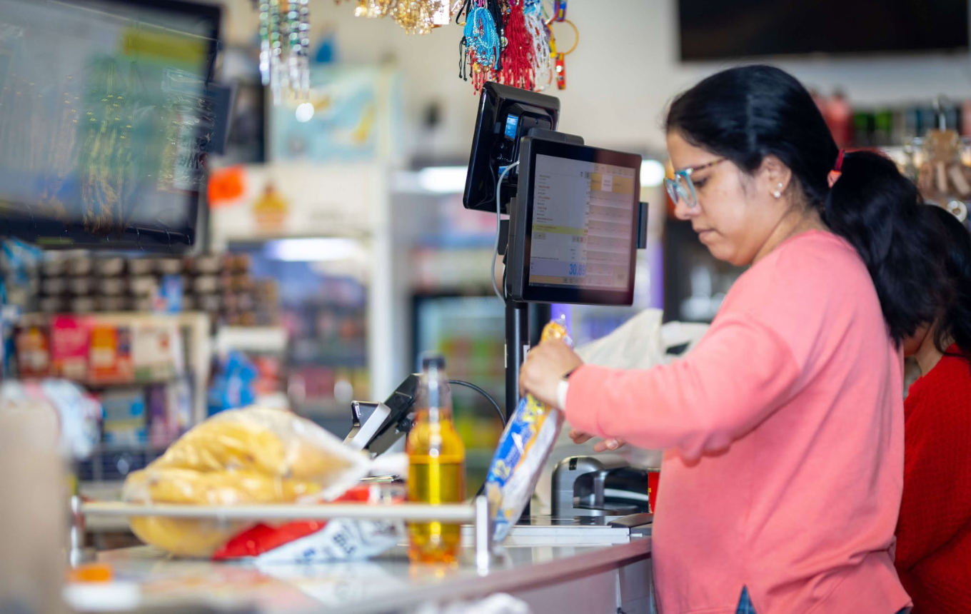 Grocery store employee scanning items at checkout on a POS system